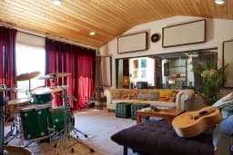 Main recording room with drums, guitar, and lounge seating at ESCAPE Studios