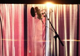 Microphone against red curtains in an ESCAPE Studios recording room