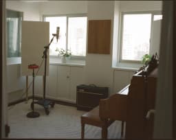 Isolation room with microphone stand and window at Room Key Studios